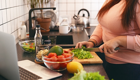 Closeup of woman cutting vegetables in kitchen