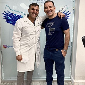 Orthodontist and patient smiling together after smile alignment