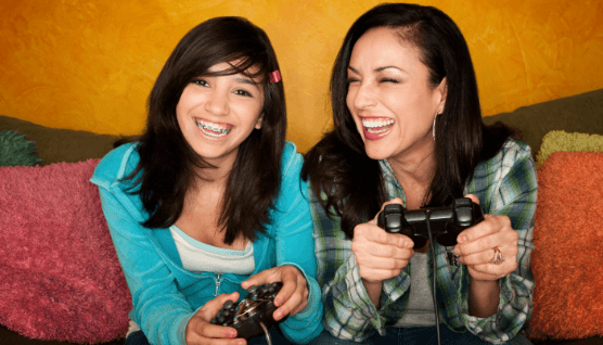 Teen with braces laughing and playing video games with mother