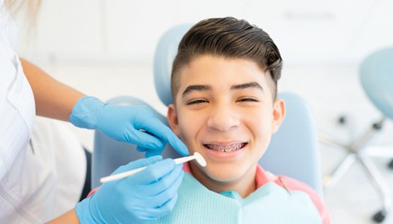 a teen with braces sitting in a dental chair