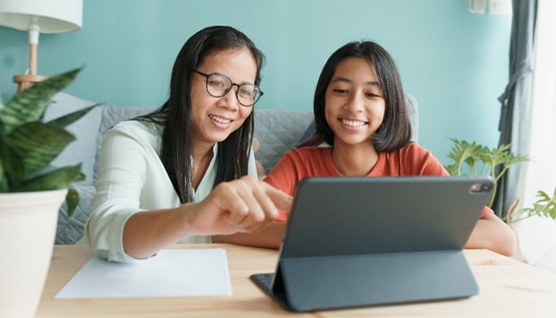 a parent and teen smiling and researching orthodontic treatment on a laptop
	