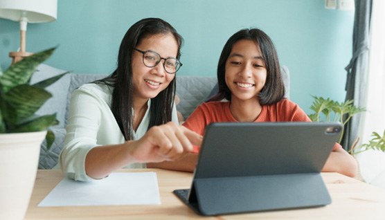 a parent and teen smiling and researching orthodontic treatment on a laptop