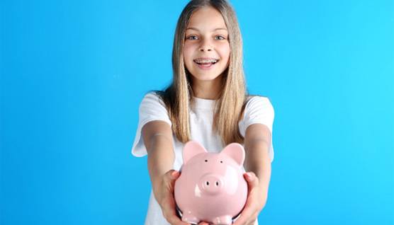girl with braces and piggy bank for cost of traditional braces in Queens  