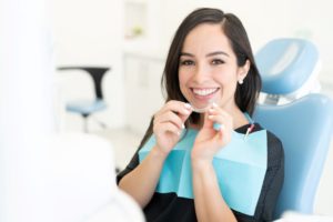 Happy dental patient holding clear aligner